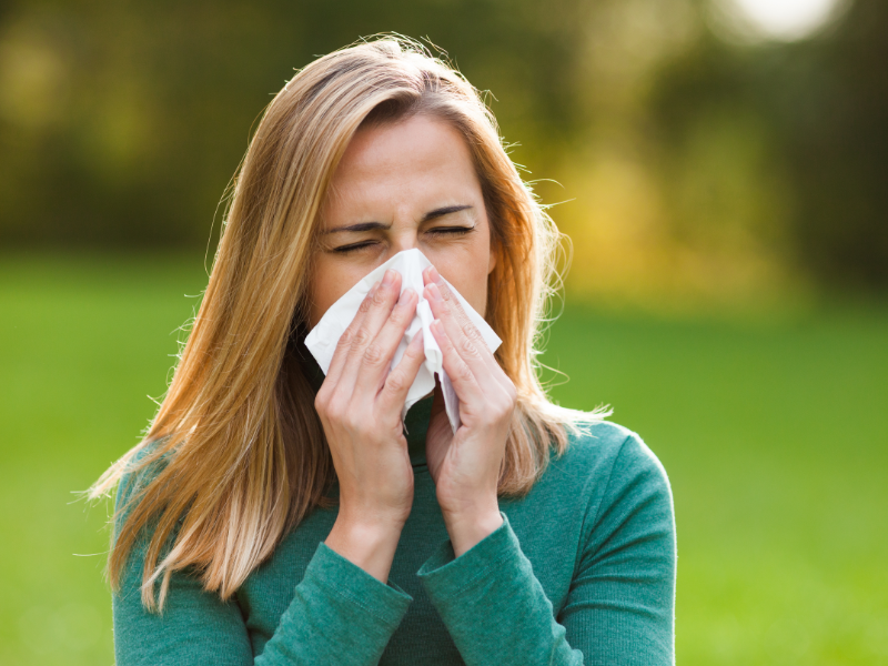 Frau niesend mit Taschentuch